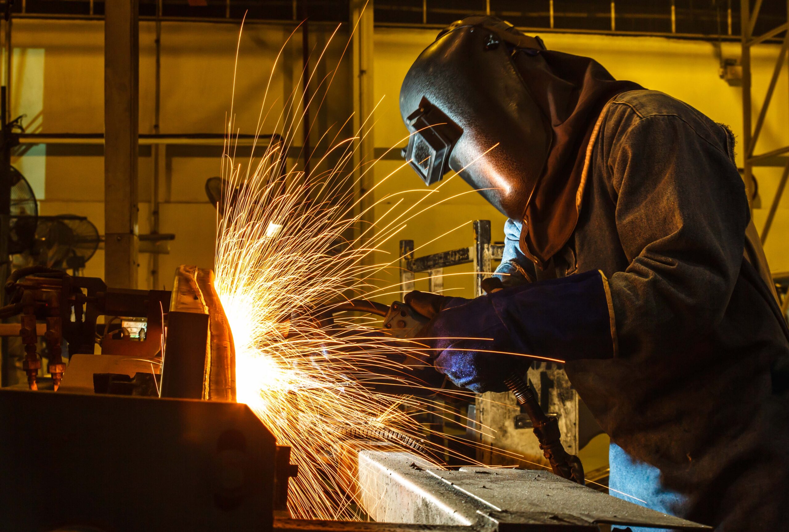 Worker, welding in a car factory with sparks, manufacturing, industry